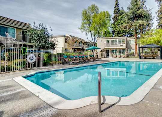 A swimming pool surrounded by a fence and trees.