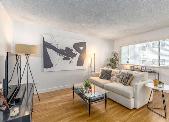 A living room with a white couch, a coffee table, and a large abstract painting on the wall.