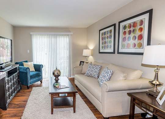 Model Living Room with Wood-Style Flooring and Patio Accessibility at Misty Ridge Apartments located in Woodbridge, VA.