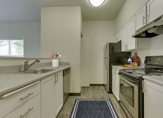 Model Kitchen with White Cabinets and Wood-Style Flooring at Landings at Morrison Apartments located in Gresham, OR.