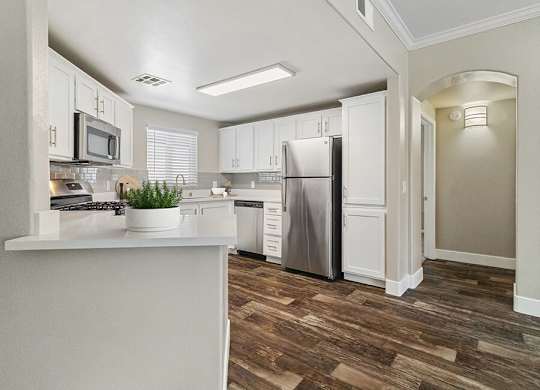 A kitchen with white cabinets and a wooden floor.