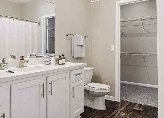 A white bathroom with a toilet, sink, and a mirror.