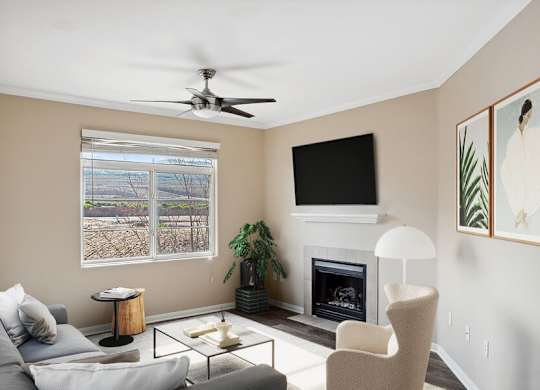 A living room with a grey couch, a fireplace, a ceiling fan, and a painting on the wall.