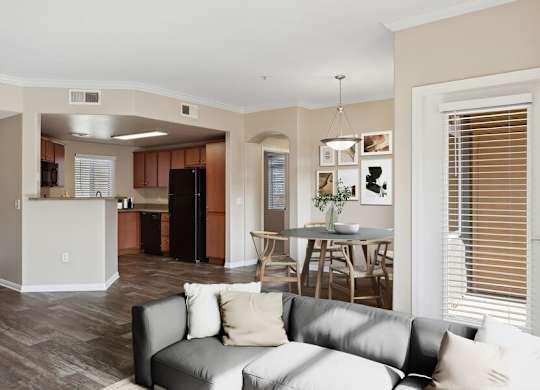 A living room with a grey couch and a kitchen in the background.