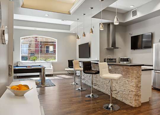 A modern kitchen with a pool table and bar stools.
