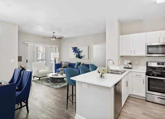 A modern kitchen with blue chairs and white cabinets.