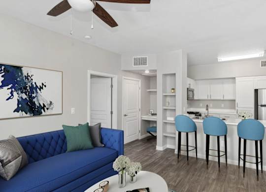 A blue couch with a white vase on a coffee table in a room with a ceiling fan.