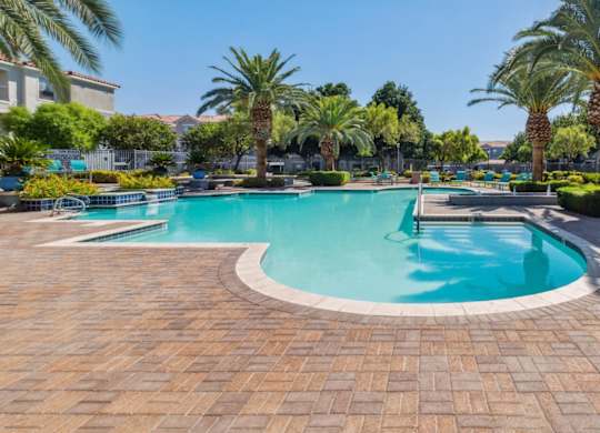 A large outdoor swimming pool surrounded by palm trees.