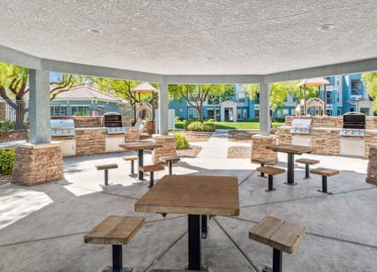 A patio with tables and benches is surrounded by a white wall.