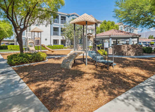 A playground with a swing set and a slide in the foreground and apartment buildings in the background.