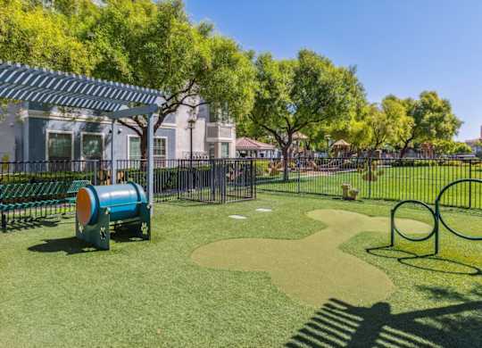 A playground with a blue barrel and a green bench.