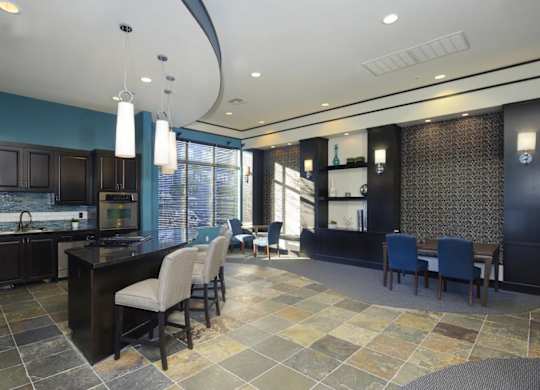 A kitchen with a black countertop and blue chairs.