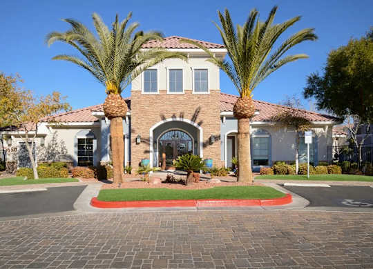 A house with a brick walkway and palm trees in front.