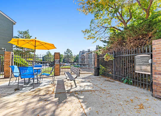 A yellow umbrella is on a blue chair on a patio.