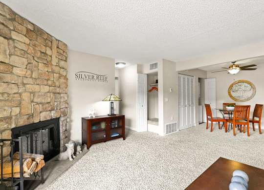 A living room with a stone fireplace and a dining table with chairs.