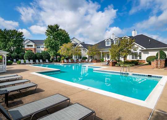 A large swimming pool surrounded by lounge chairs and trees.