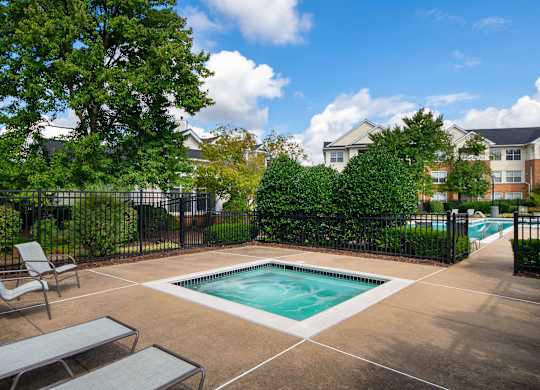 A small pool surrounded by a black fence and a bench.