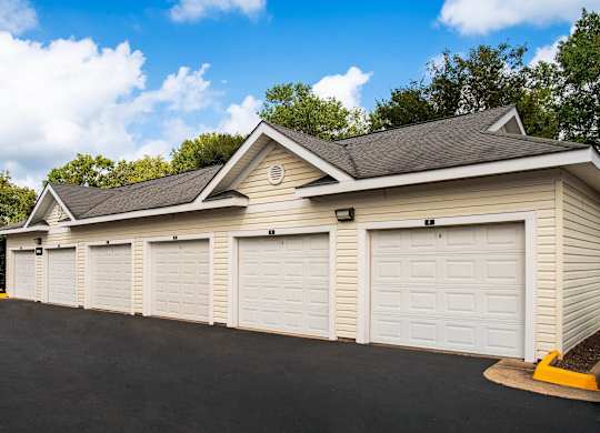 A row of white garage doors in front of a building.