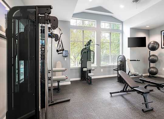 A home gym with a variety of equipment including a treadmill, weights, and a bench press.