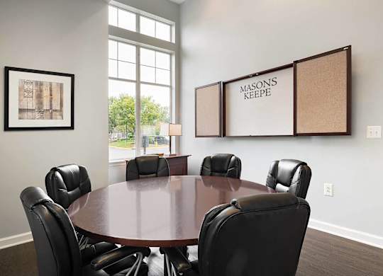 A conference room with a large table surrounded by chairs and a cork board on the wall.