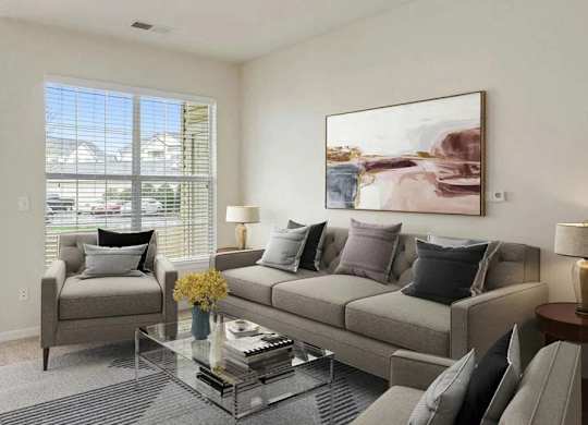 A living room with a grey couch, a coffee table, and a painting on the wall.