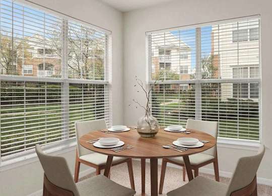 A dining room with a table set for two and a view of the outside.