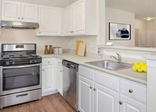 A white kitchen with a stainless steel refrigerator and oven.