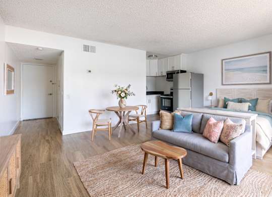 A living room with a grey couch, a wooden coffee table, and a dining table with chairs.