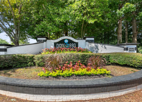 a retaining wall with flowers and trees in the background