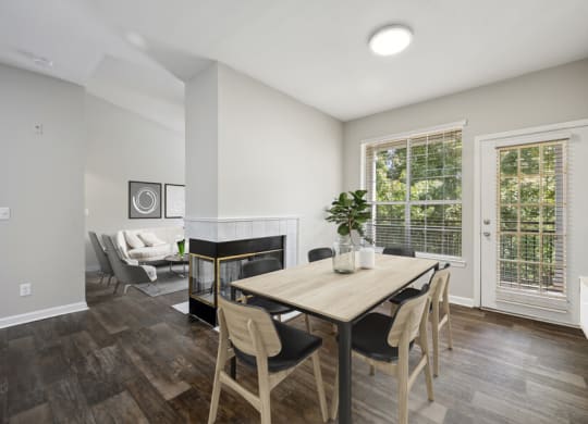 a dining area with a wooden table and chairs and a fireplace in the background