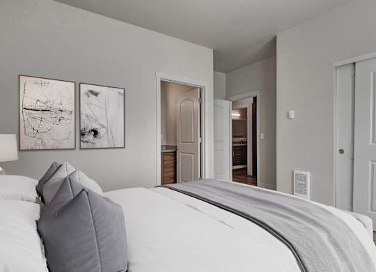 A bedroom with a large bed and two framed pictures on the wall.