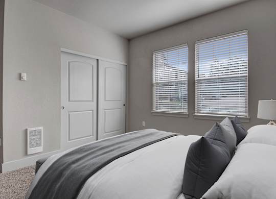 A bedroom with a large bed and two windows.