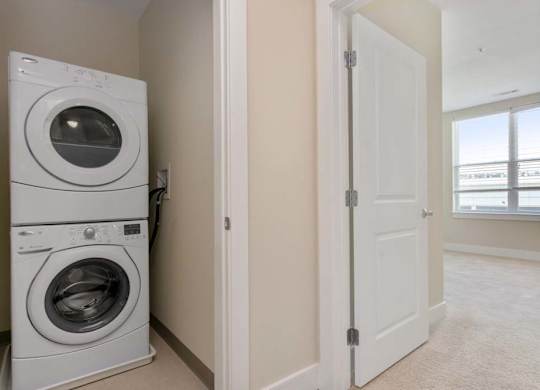 A white dryer and washer are stacked on top of each other in a laundry room.