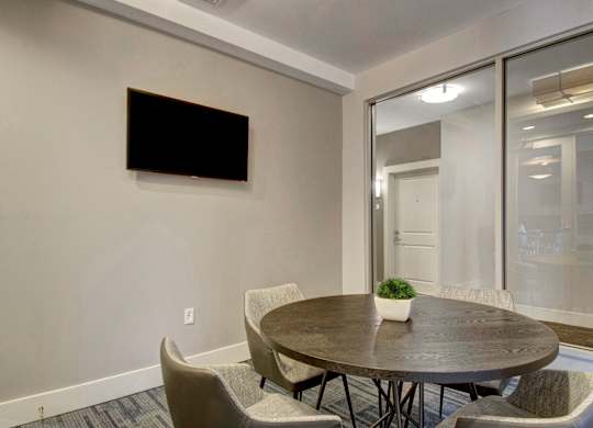 A conference room with a table, chairs, and a television on the wall.