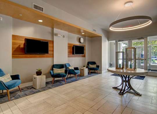 A spacious waiting area with blue chairs and a television mounted on the wall.