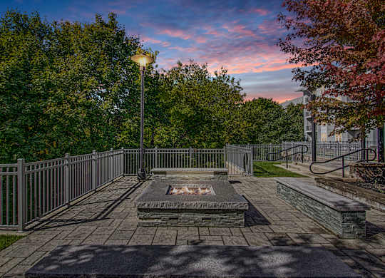 A park with a fire pit surrounded by a fence.