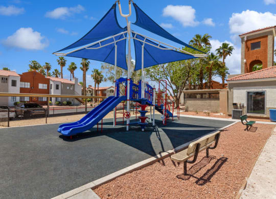 a playground with a blue slide and umbrella at villas at houston levee west apartments