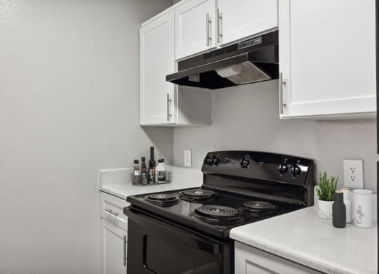 a kitchen with white cabinets and a black stove top oven