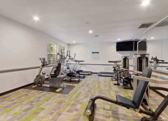 Federal Way, WA, Apartments Near Walmart - Sunset Three Twenty - A Fitness Center With Cardio Machines, Weight Equipment, Wall Mirrors, And Mounted Television Screens.