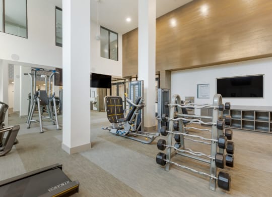 a gym with cardio equipment and a flat screen tv