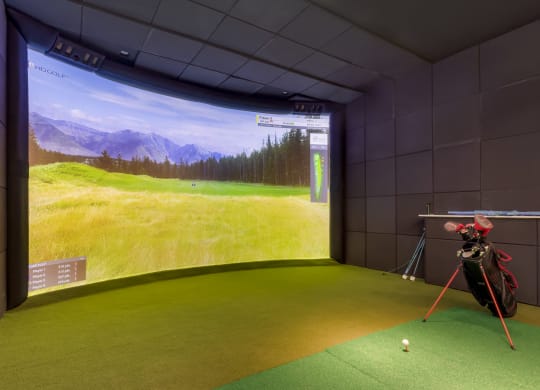 a golf simulator in a room with a view of a golf course
