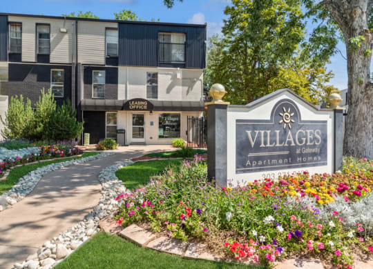 a building with a sign that says villages apartments with flowers in front of it