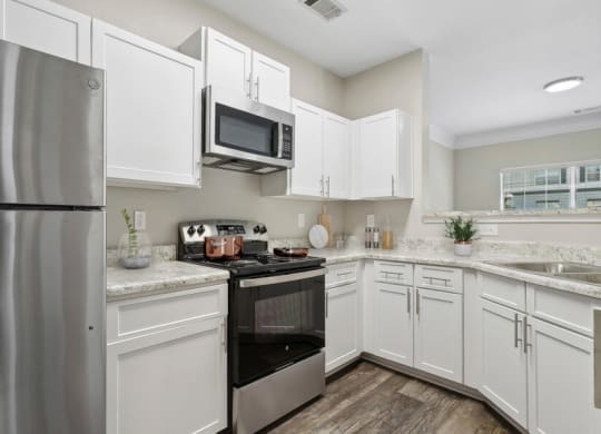 Model apartment kitchen with stainless steel appliances and white cabinets
