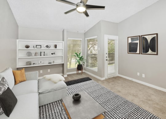 Model apartment living room with a couch and a ceiling fan