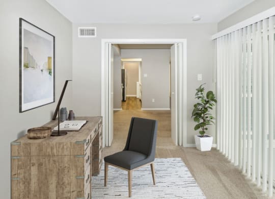 a living room with a desk and a door to a hallway