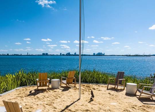 a view of the water from a beach with chairs on the sand at The Hamilton, Miami, FL