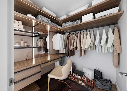 A walk in closet with clothes hanging and shelves with boxes.