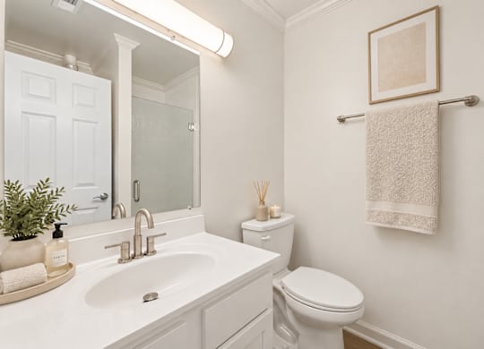 A white bathroom with a toilet, sink, and towel rack.