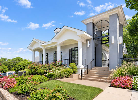 A white house with a black fence and a green lawn.