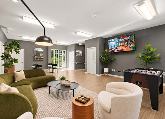 A living room with a green couch, a coffee table, and a television.